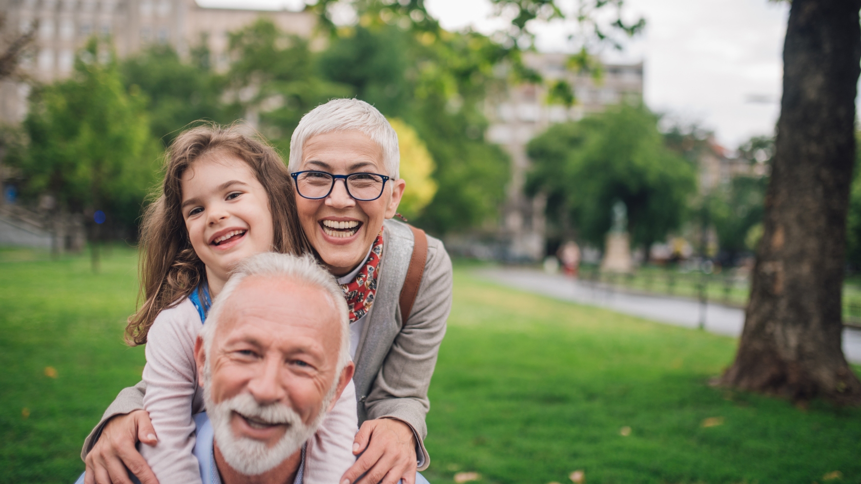 Three people smiling together in a park.